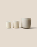 Three frosted glass candle holders in different sizes arranged in ascending order of height against a solid beige background.