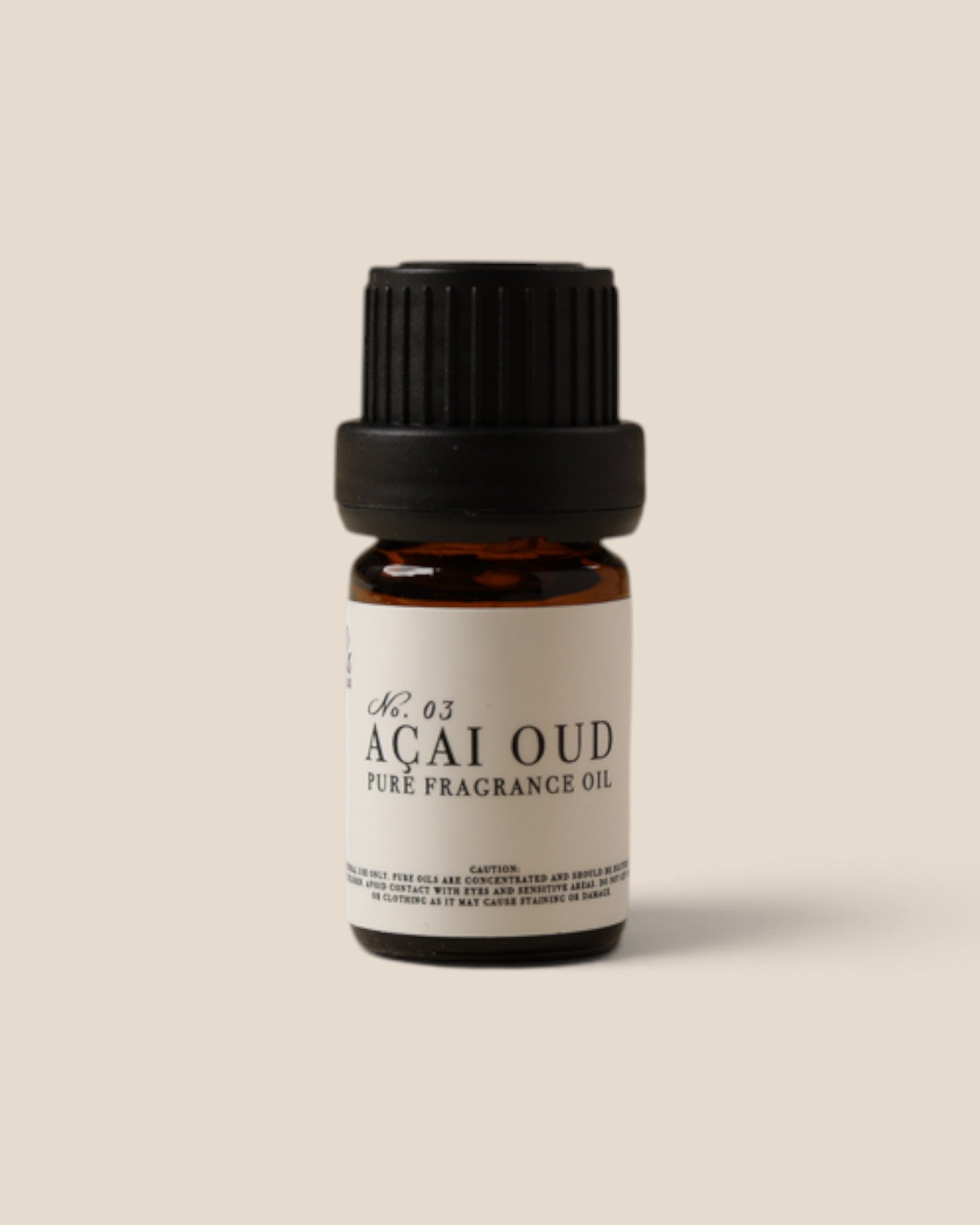 A small amber glass bottle of Acai Oud pure fragrance oil with a black ribbed cap and a white label, centered on a solid beige background.