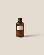 An amber glass bottle with a black cap and a white label reading 'Bora Bora', centered against a solid beige background.