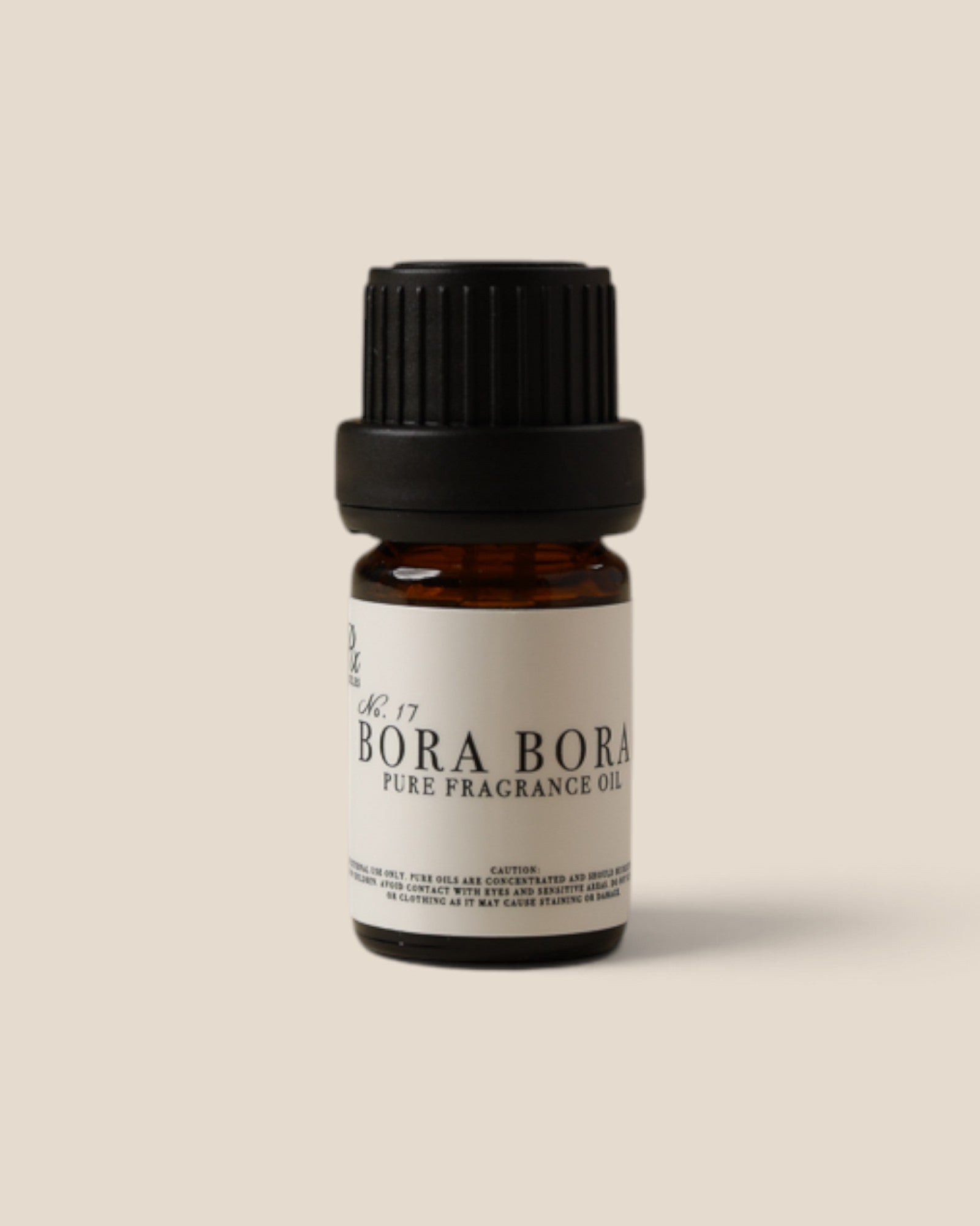A small amber glass bottle of Bora Bora pure fragrance oil with a black ribbed cap and a white label, centered on a solid beige background.