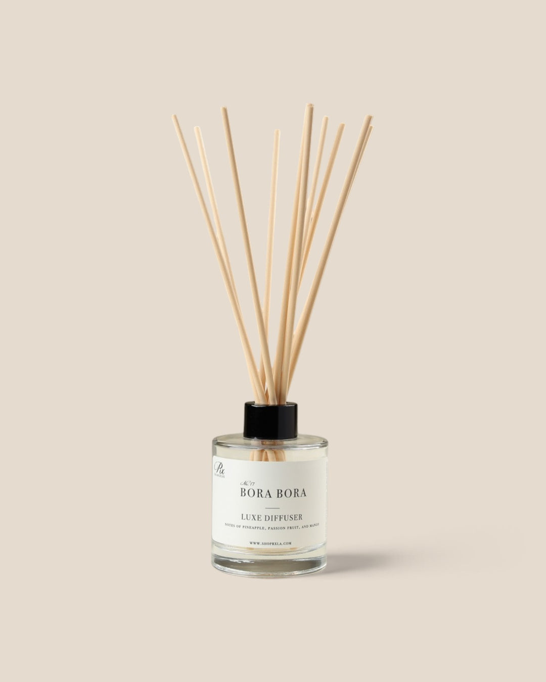 A reed diffuser bottle with a clear glass container, pale liquid, and fiber reeds, featuring a black cap and a white label that reads 'BORA BORA'.