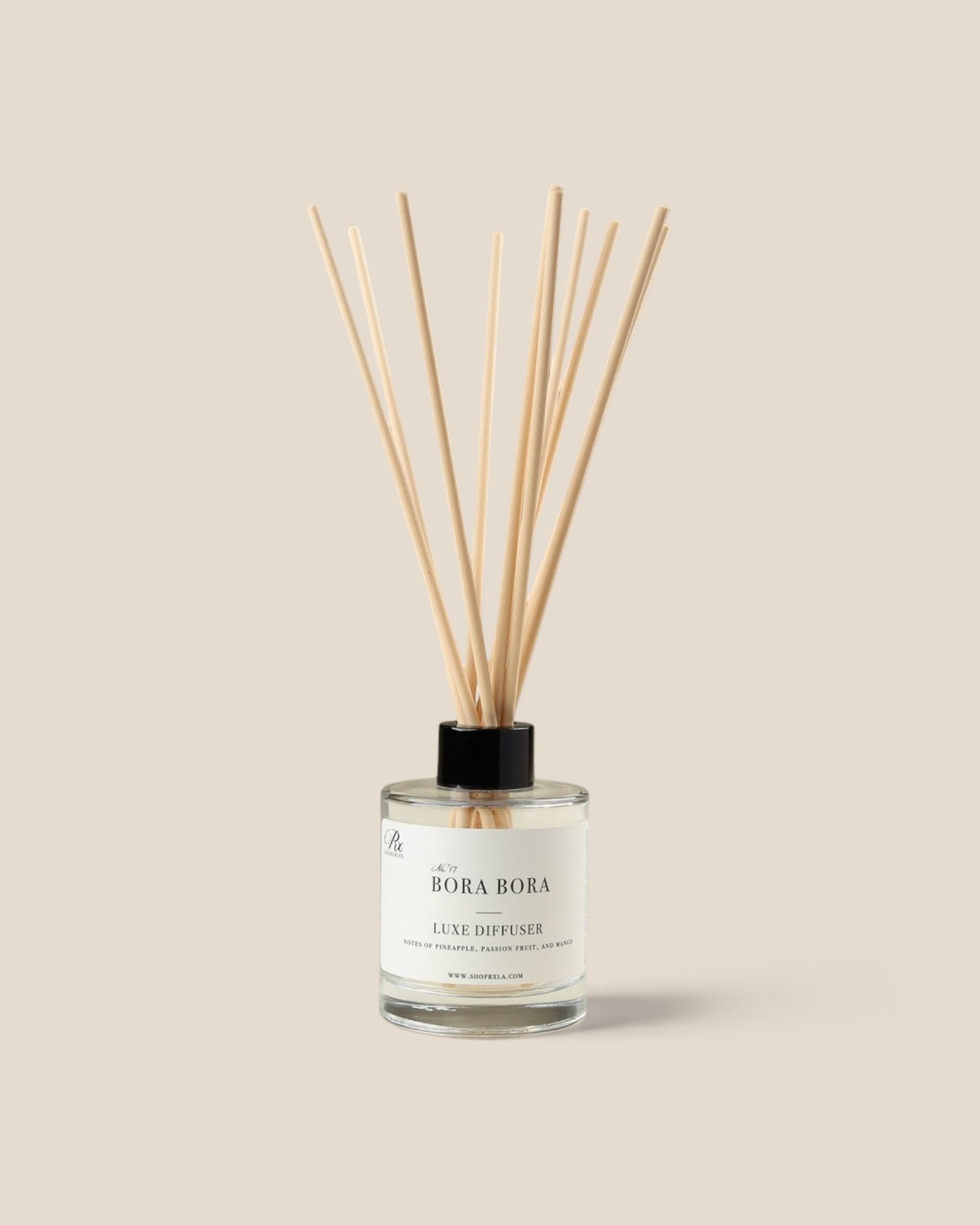 A reed diffuser bottle with a clear glass container, pale liquid, and fiber reeds, featuring a black cap and a white label that reads 'BORA BORA'.