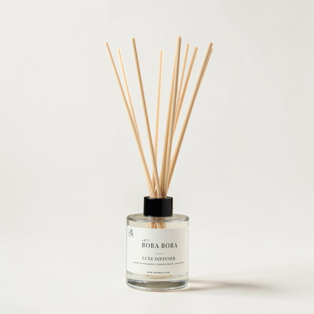 A Bora Bora Luxe Diffuser with a clear glass bottle, white label, and natural light wood reeds, set against a clean off-white background.