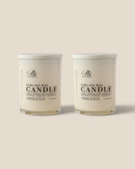 Two white soy wax candles in clear glass jars with white lids, shown side by side on a light beige background. The label reads 'PURE SOY WAX CANDLE'.