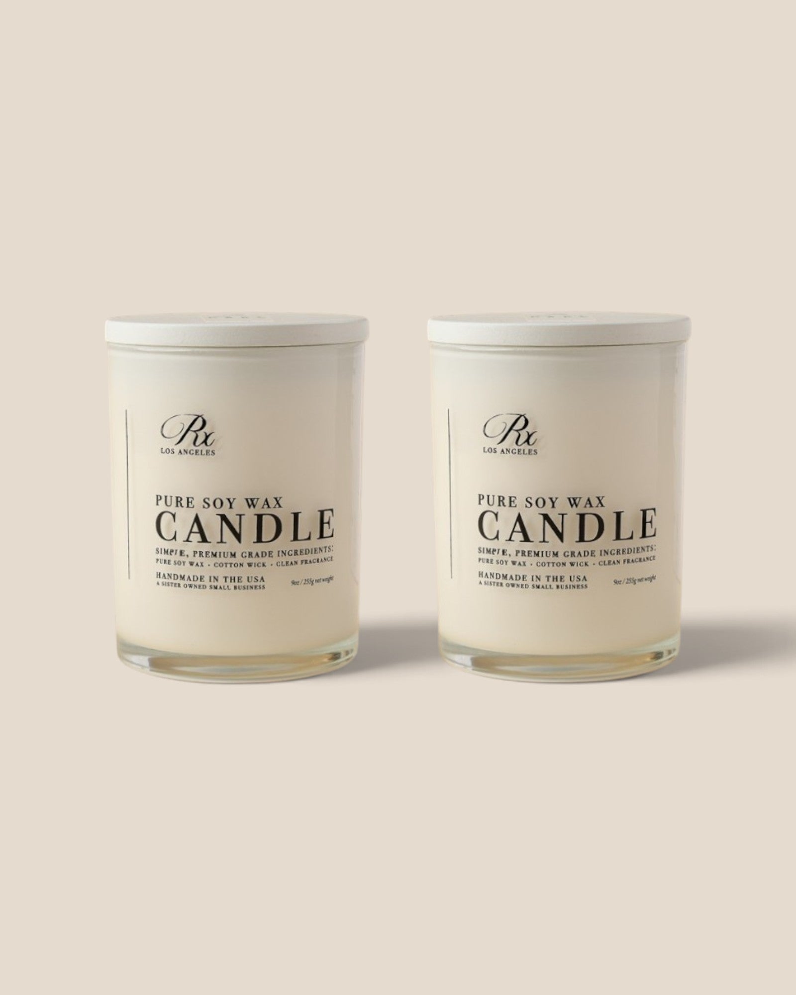 Two white soy wax candles in clear glass jars with white lids, shown side by side on a light beige background. The label reads 'PURE SOY WAX CANDLE'.