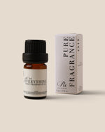 A small amber glass bottle of fragrance oil with a black cap stands next to its white product box on a plain warm beige background. The label reads 'Everything Pure Fragrance Oil' and the box reads 'Pure Fragrance Oil'.
