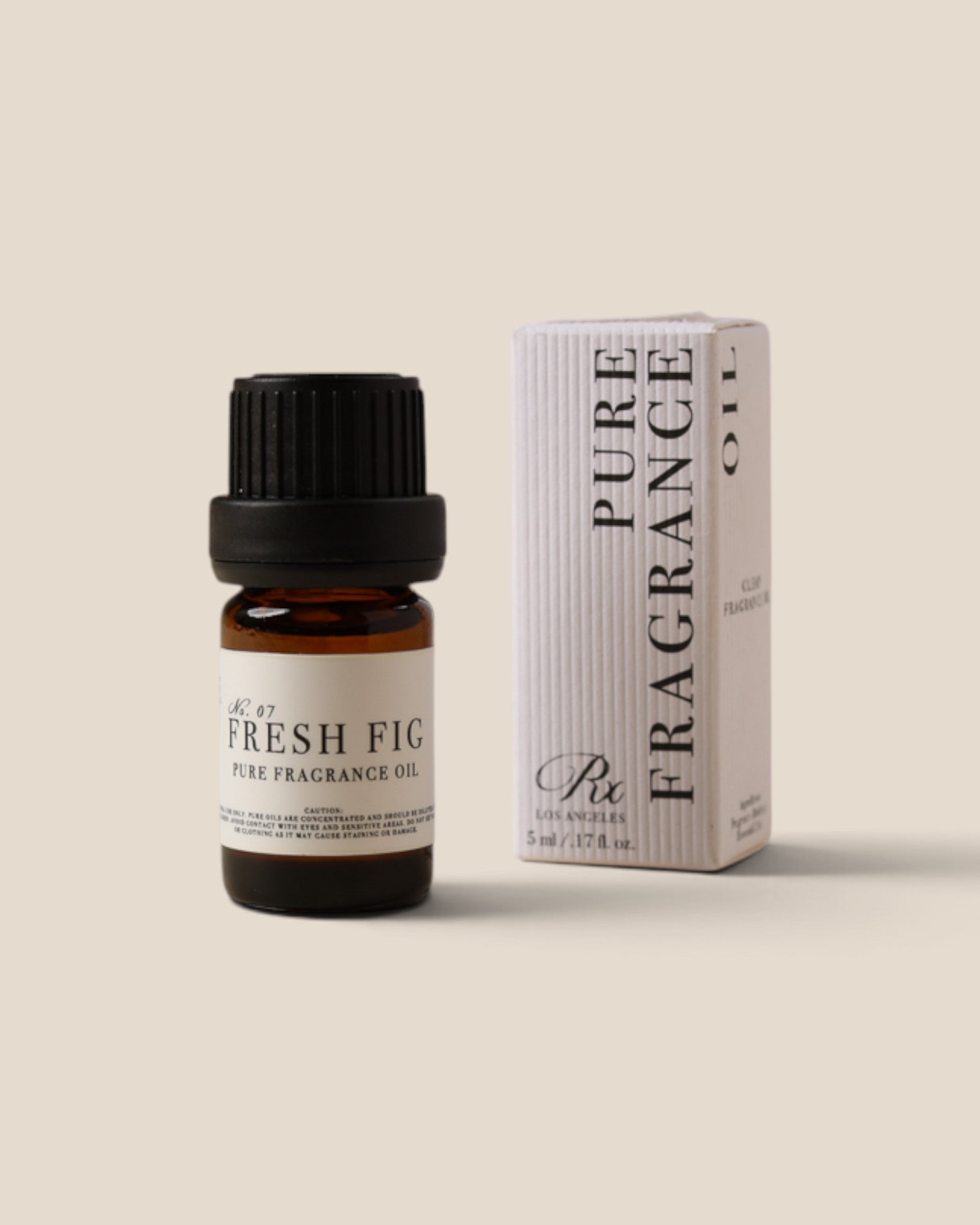 A bottle of Rx Pure Fragrance Oil with 'Fresh Fig' scent next to its white packaging box, set against a solid beige background.