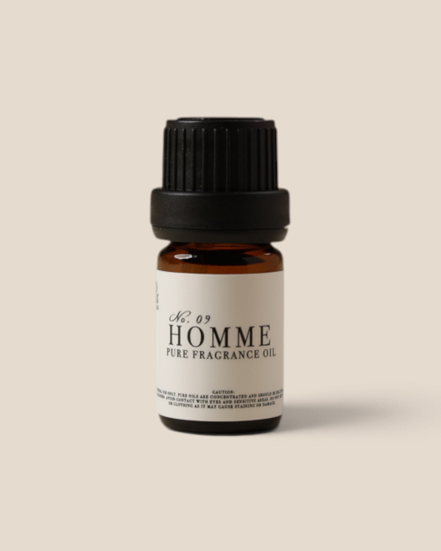 A small amber glass bottle of fragrance oil with a black ribbed cap and a white label reading 'No. 09 HOMME PURE FRAGRANCE OIL', centered on a plain warm beige background.