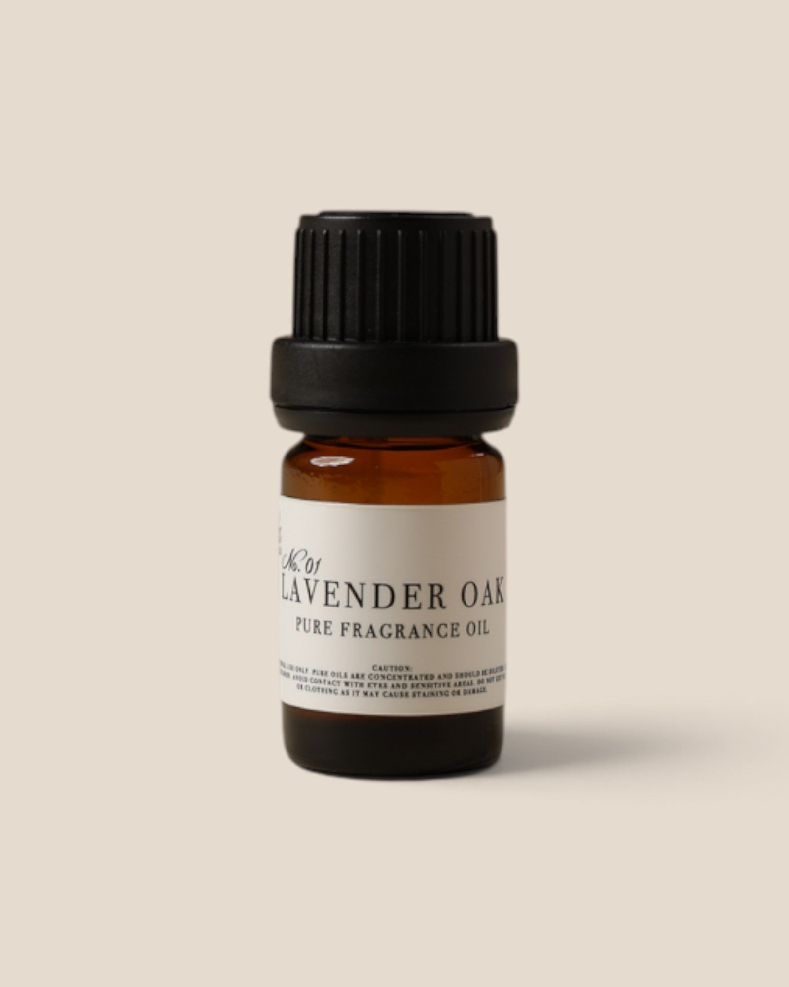 A small amber glass bottle of Lavender Oak Pure Fragrance Oil with a black ribbed cap and a cream label, centered on a solid beige background.