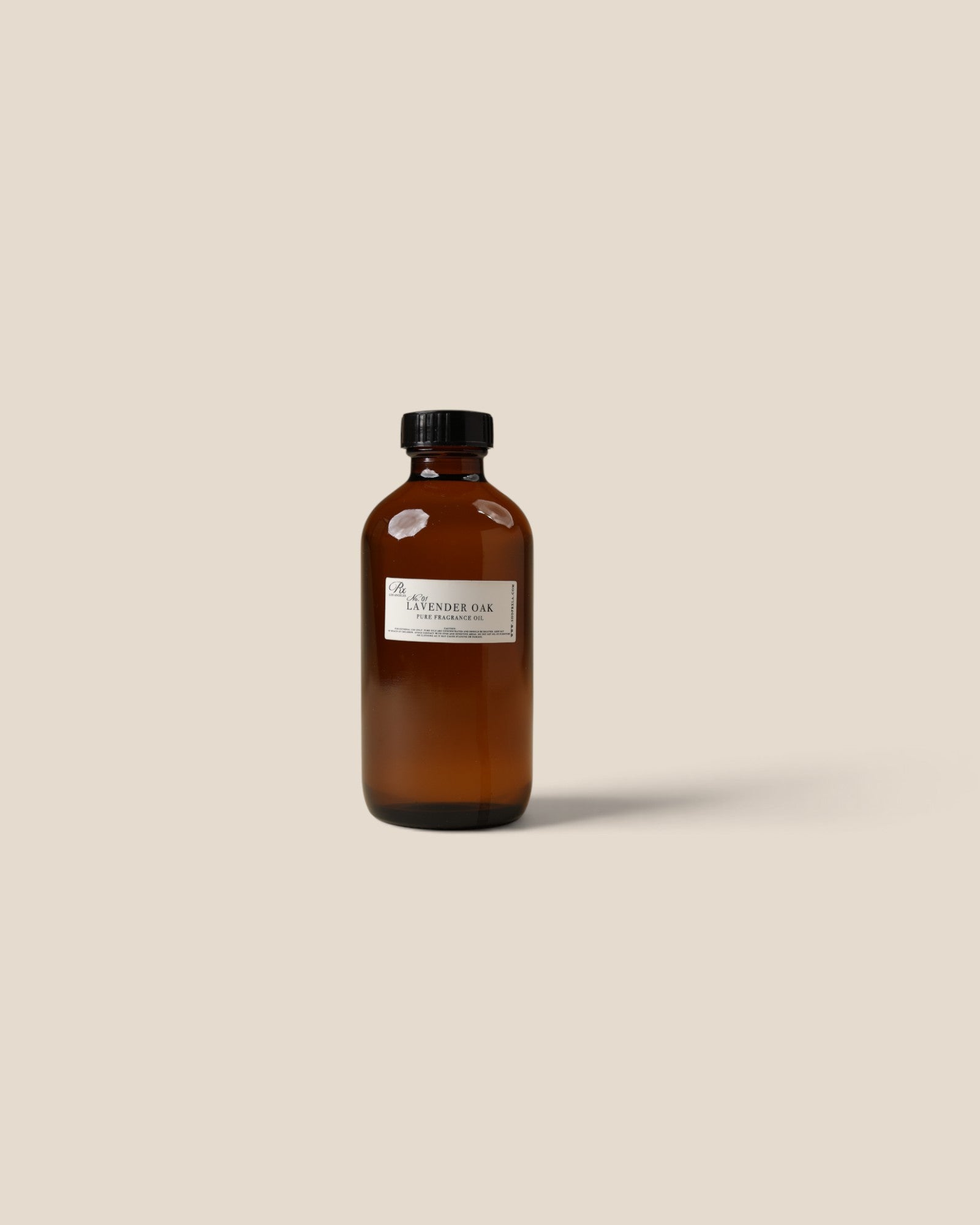 An amber glass bottle with a black cap and a white label reading 'PURE FRAGRANCE Oil', centered on a solid beige background.