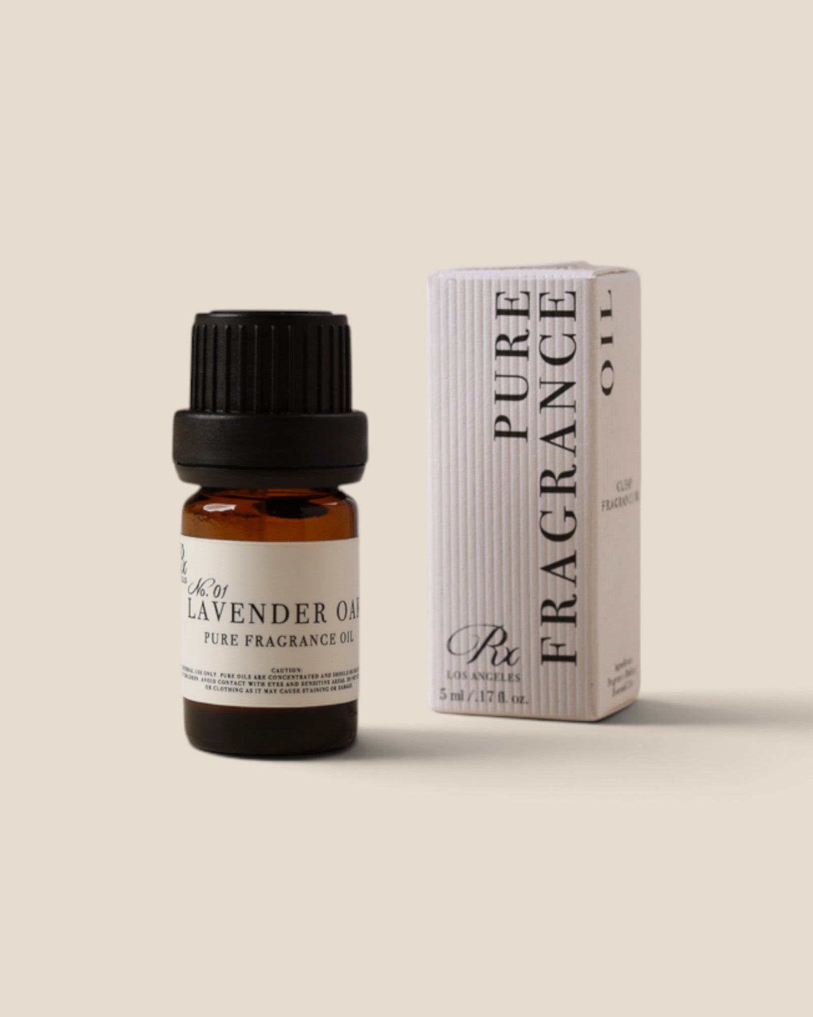 A bottle of Lavender Oil fragrance oil next to its white packaging box, both featuring black text and a black cap, set against a solid beige background.