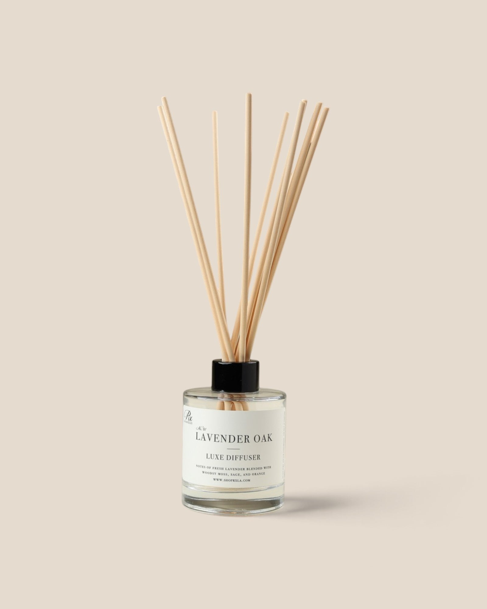 A reed diffuser bottle with fiber reeds, a clear glass container, and a black cap, labeled 'Lavender Oak', set against a solid beige background.