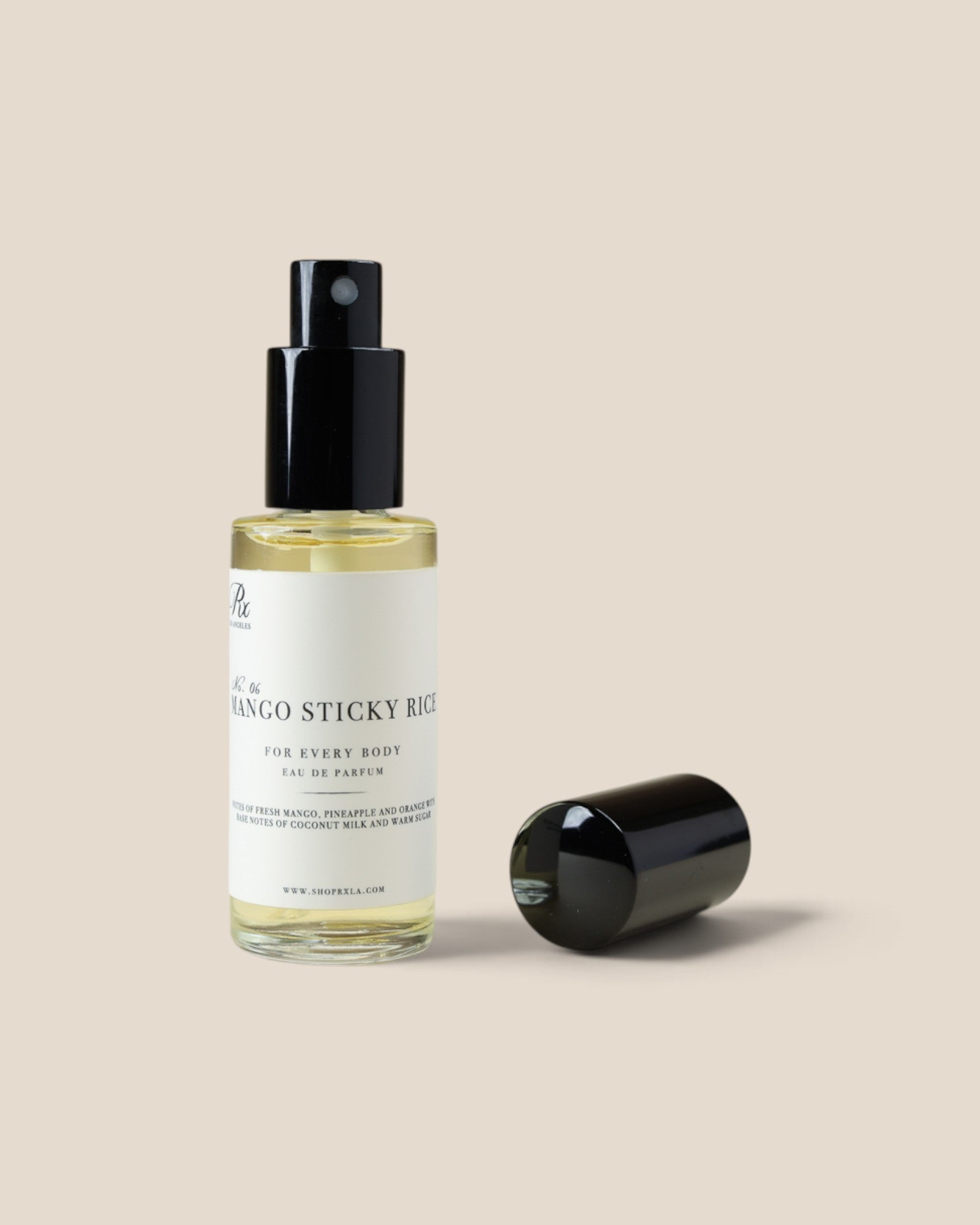 A clear glass bottle of blanco sticky bud essential oil with a black spray pump and white label, shown next to its detached black cap on a solid beige background.
