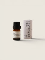 A small amber glass bottle of lavender oil with a black cap stands next to its white box packaging on a warm off-white background. The box is labeled 'PURE FRAGRANCE' and 'Lavender Oil'.