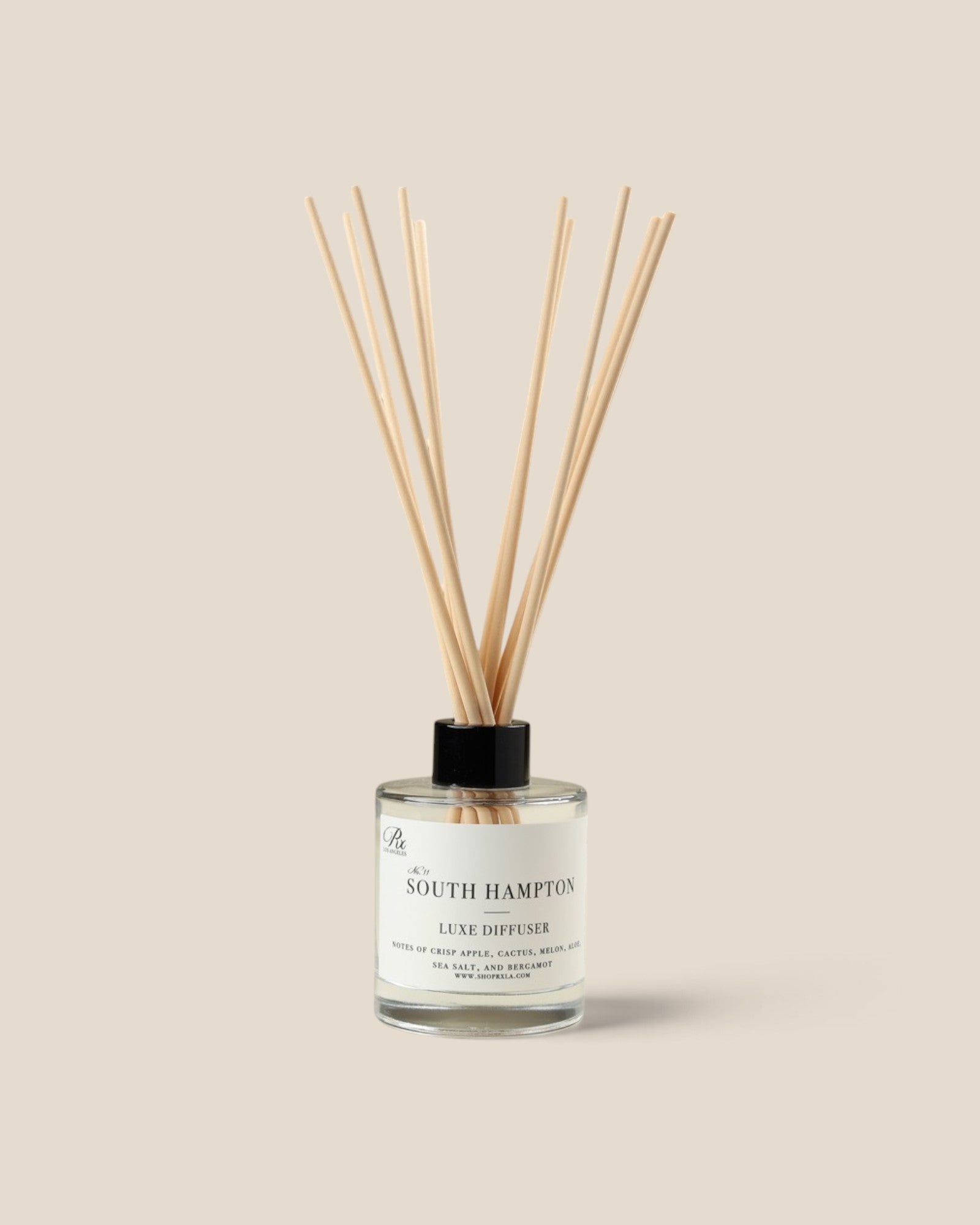A glass reed diffuser bottle with a black cap and natural wood reeds, labeled 'A SOUTH HAMPTON LUXE DIFFUSER', centered on a solid beige background.