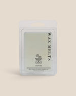 A packaged wax melt product in a clear plastic clamshell package with a white backing card, shown against a solid light beige background. The label reads 'WAX MELTS' and 'HOMME'.