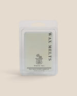 A wax melt package labeled 'WAX MELTS' and 'WHITE TEA' in a clear plastic clamshell pack on a solid light beige background.