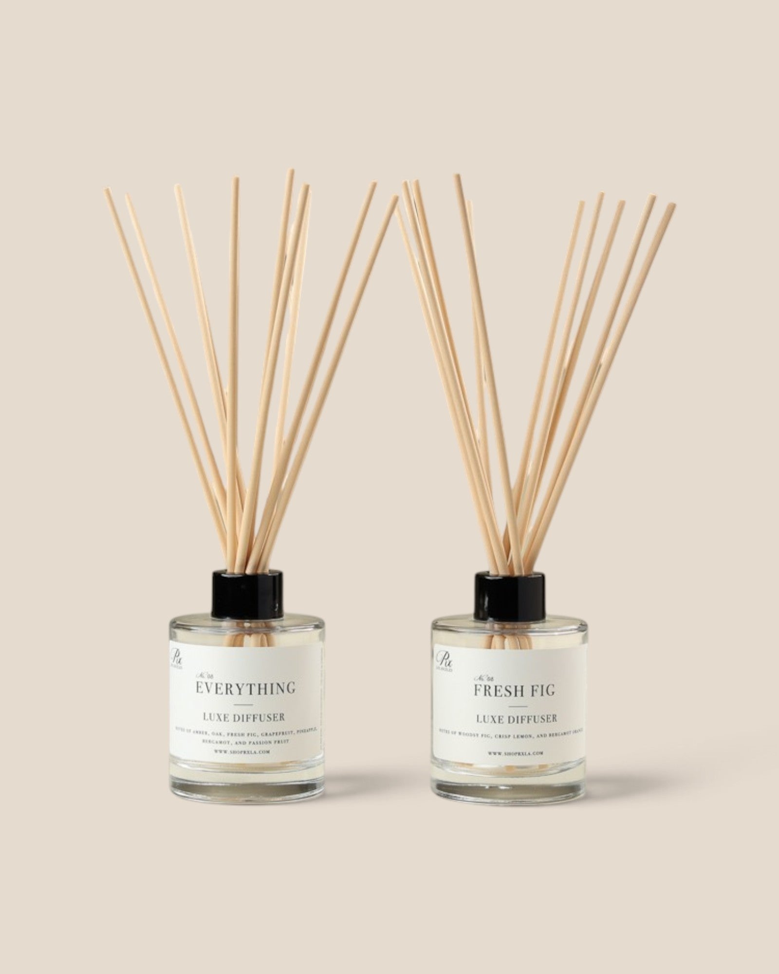 Two reed diffusers with fiberreeds and white labels on clear glass bottles, set against a solid beige background. The left bottle is labeled 'the EVERYTHING' and the right bottle is labeled 'the FRESH FIG'.