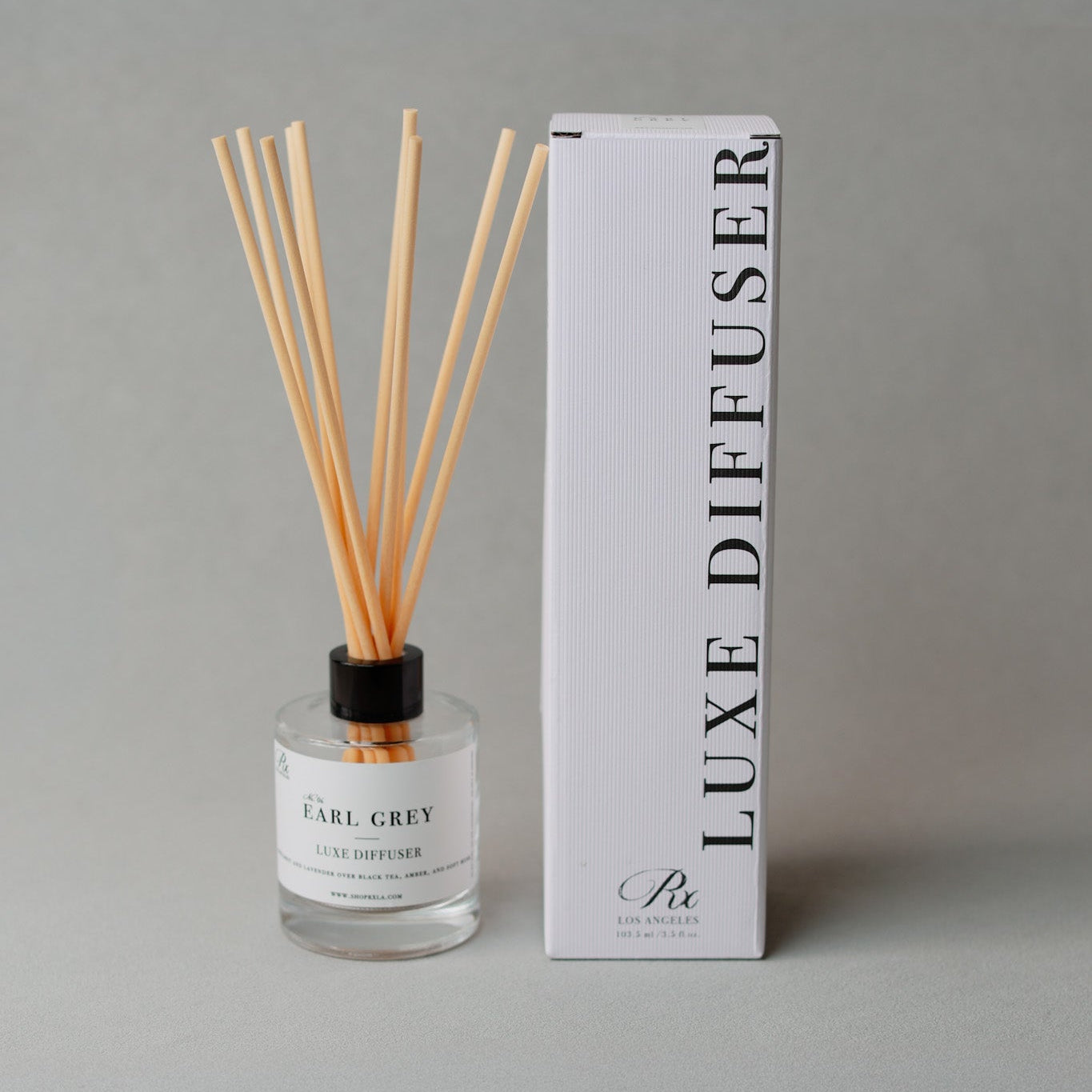 Glass reed diffuser with golden liquid and black reeds—Earl Grey scent features bergamot, lavender, black tea, amber, and musk for a calm, elegant aroma