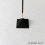 Black 3D printed holder hanging against a white background