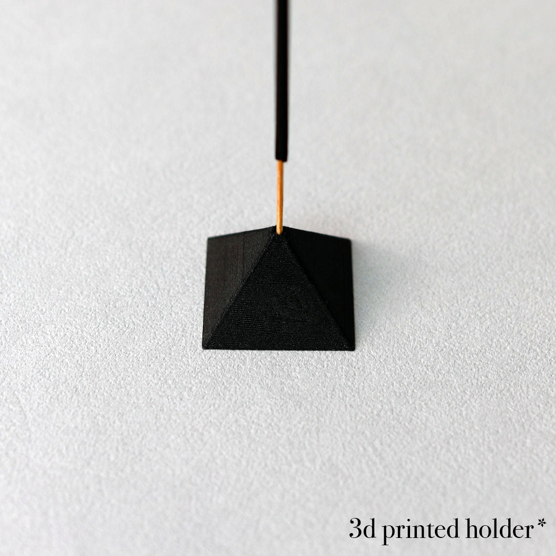 Black 3D printed holder hanging against a white background