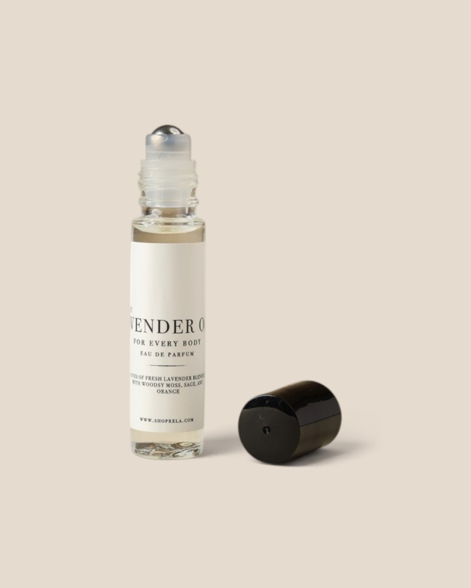 A clear glass rollerball perfume bottle with a white label and black text, shown next to its detached black cap on a solid beige background.