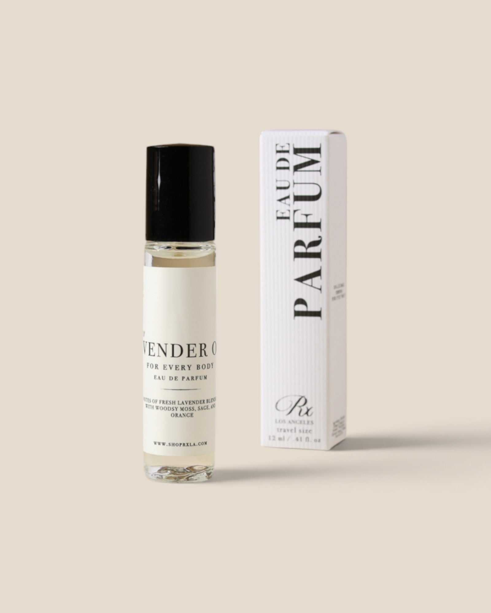 A clear glass rollerball perfume bottle with a black cap stands next to its white box packaging, both featuring black text that reads 'Eau de Parfum' 
